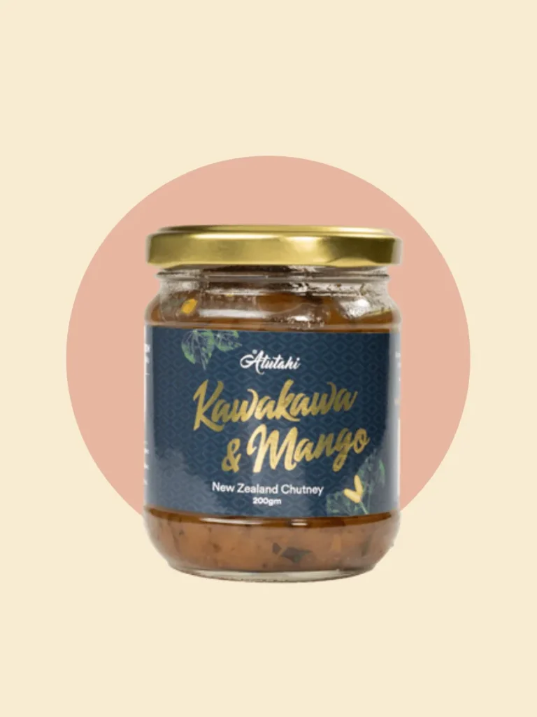 A glass jar containing kawakawa and mango New Zealand Chutney sauce, featuring a rich orange hue and a decorative label.
