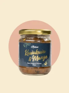 A glass jar containing kawakawa and mango New Zealand Chutney sauce, featuring a rich orange hue and a decorative label.