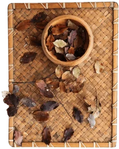 Fresh leaves arranged in a bowl on a bamboo mat, showcasing a simple, natural aesthetic