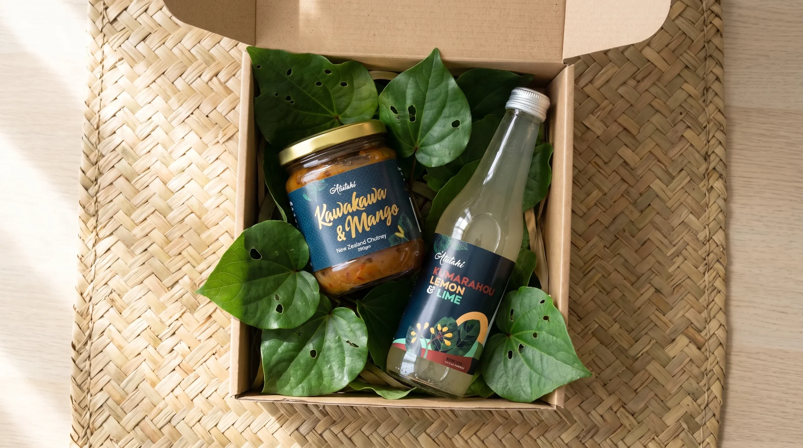 Wellness gifts NZ flat lay with Atutahi native drink, chutney and kawakawa soap on a woven mat.
